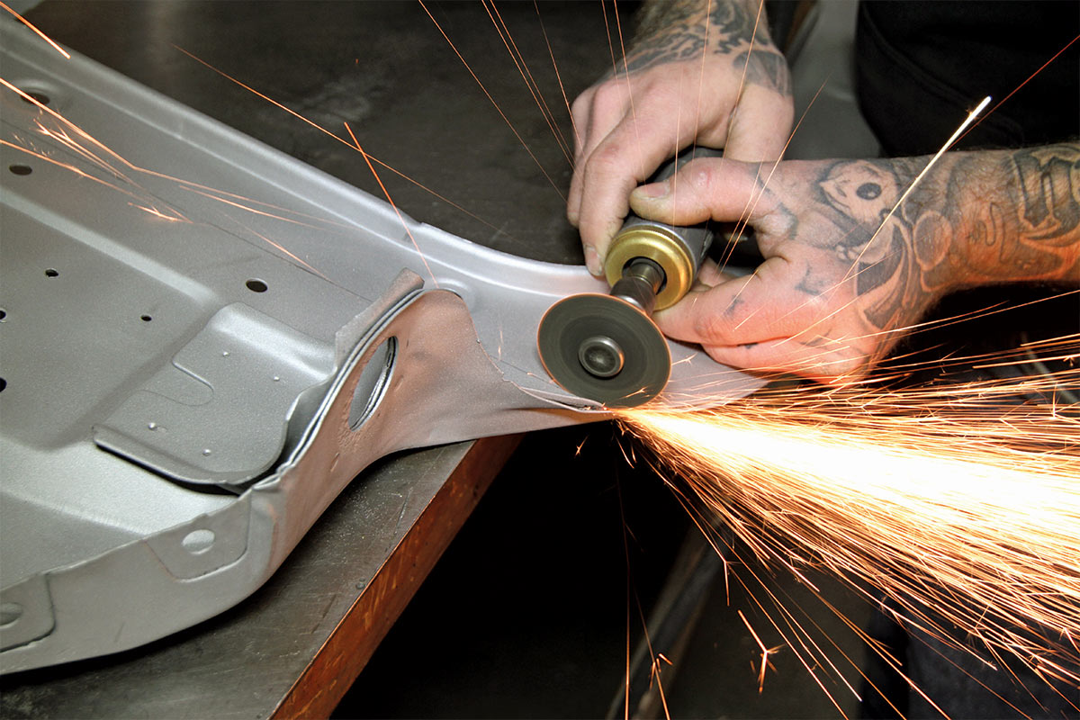 Hands using a small rotary saw on a car body