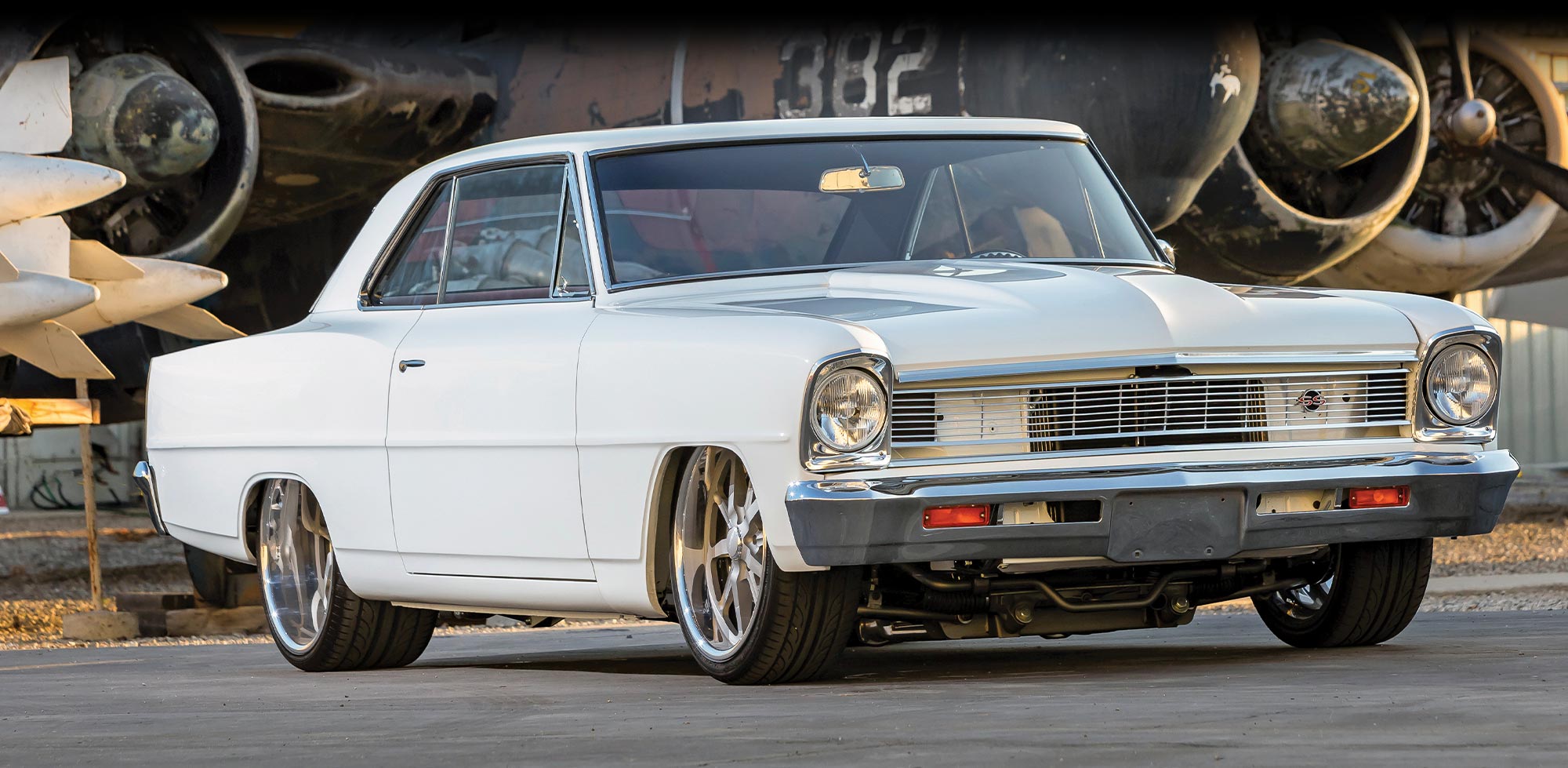 quarter passenger side view of Christian Peich’s white ’66 Chevy Nova SS parked on the tarmac of an old aircraft hanger