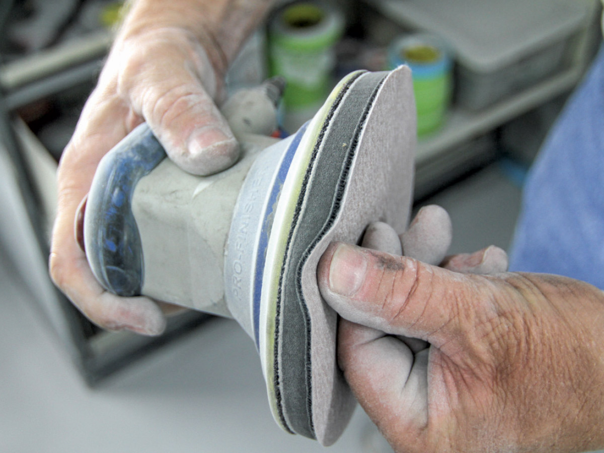 Thumb pushing into cushion pad of dual-action sander