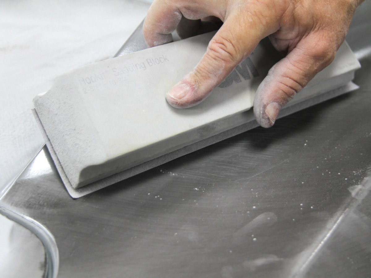 Hand holding a white sanding block at an angle
