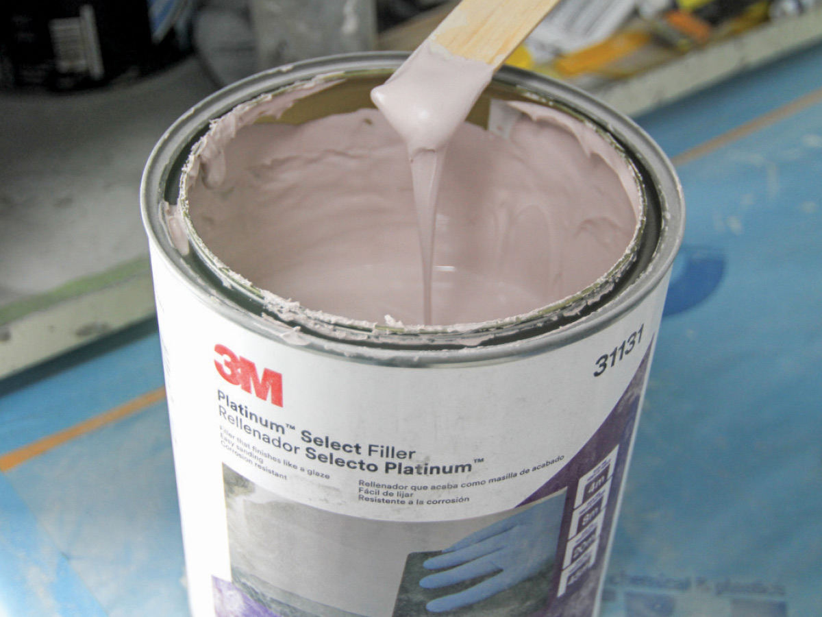 Wooden stick dipped in an open can of 3M's Platinum Select Filler sitting on a blue surface
