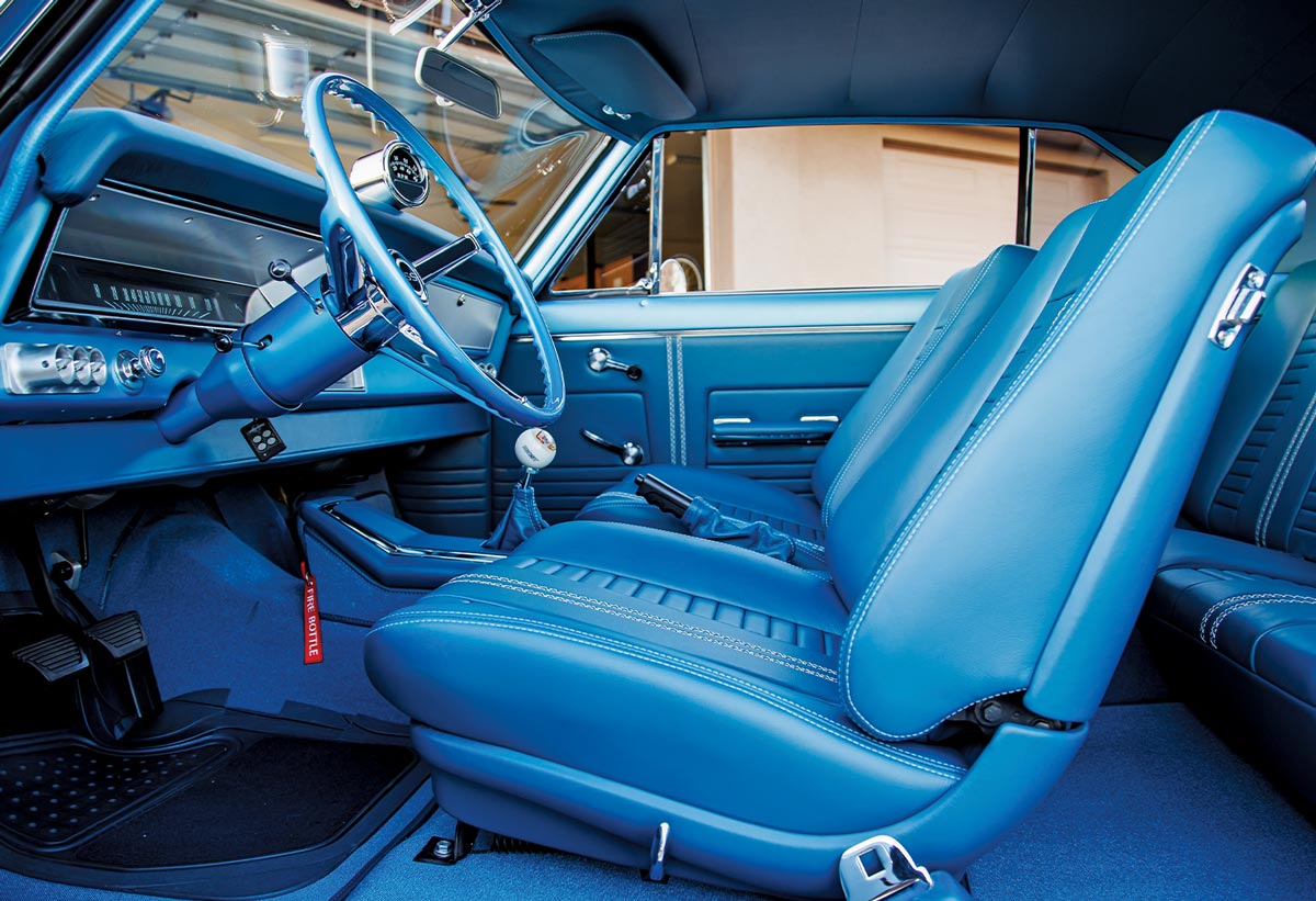 low angle view through the open driver side door at the Marina Blue ’67 Nova SS front seating featuring buckets seats lined with blue leather accented with center white stripes and custom white stitching