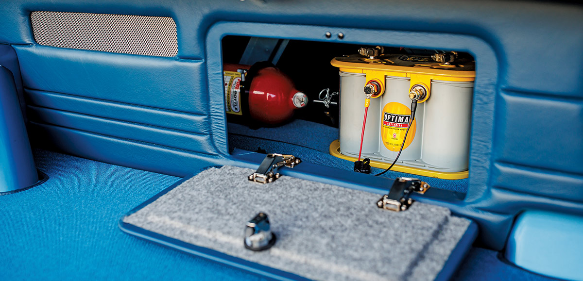 close view of a compartment in the ’67 Nova SS that holds a battery component and a fire extinguisher