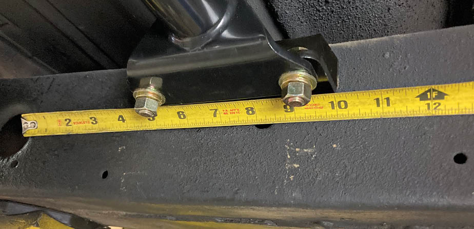 The transmission mounting brackets are attached to both ends of the crossmember and checked for even alignment with an existing feature on the stock frame.