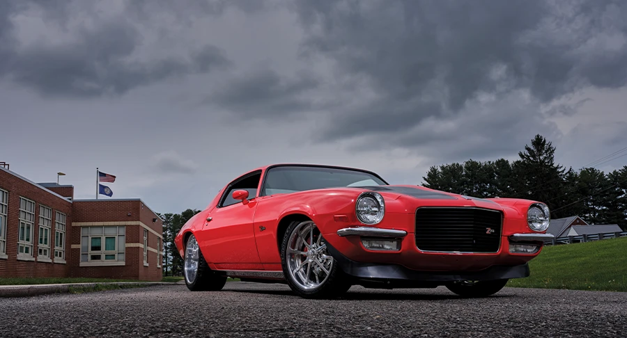 3/4 view of red and black '70 Camaro with an overcast sky