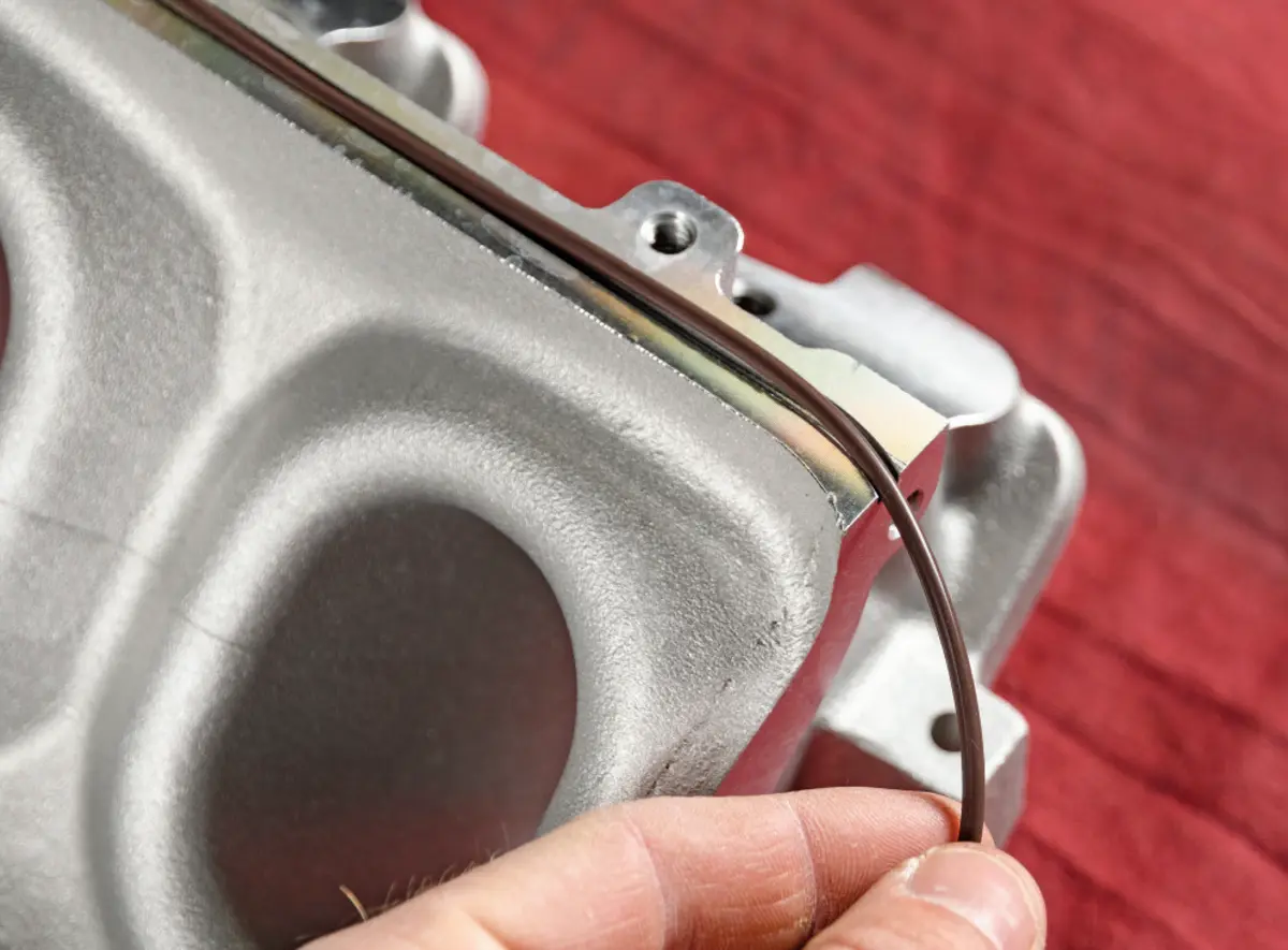 close view of a hand placing a supplied rope gasket in the top cover O-ring groove of the Holley Lo-Ram intake