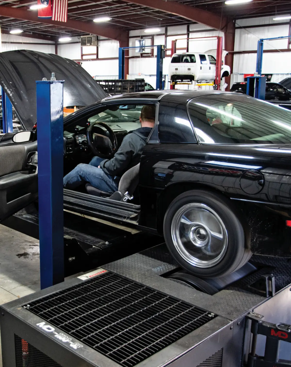 angled view of a man sitting in the driver seat of the Camaro, parked in a workshop and getting dyno tuned