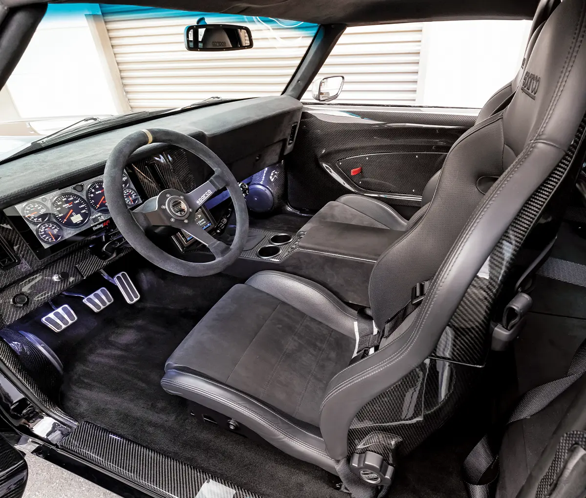driver side interior of the Twin-Turbo ’69 Camaro featuring carbon fiber lining and black leather upholstery
