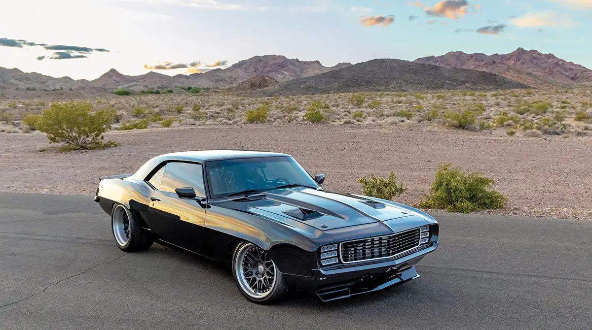 high angle wide passenger side view of the Tuxedo black Twin-Turbo ’69 Camaro parked against a bare desert landscape