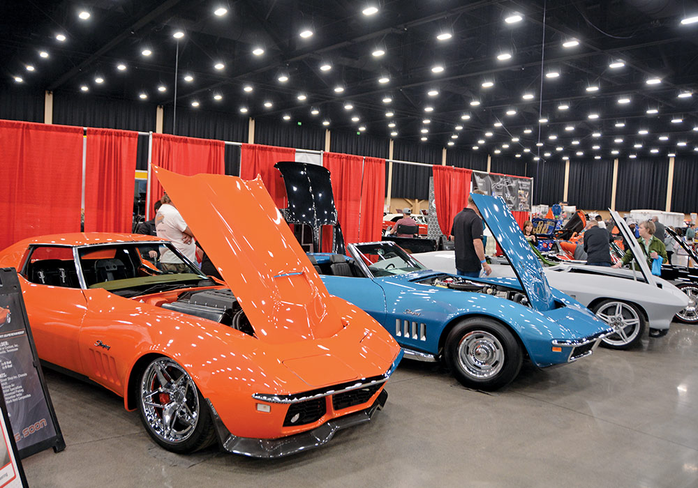 orange, blue, and grey cars lined up with their hoods open