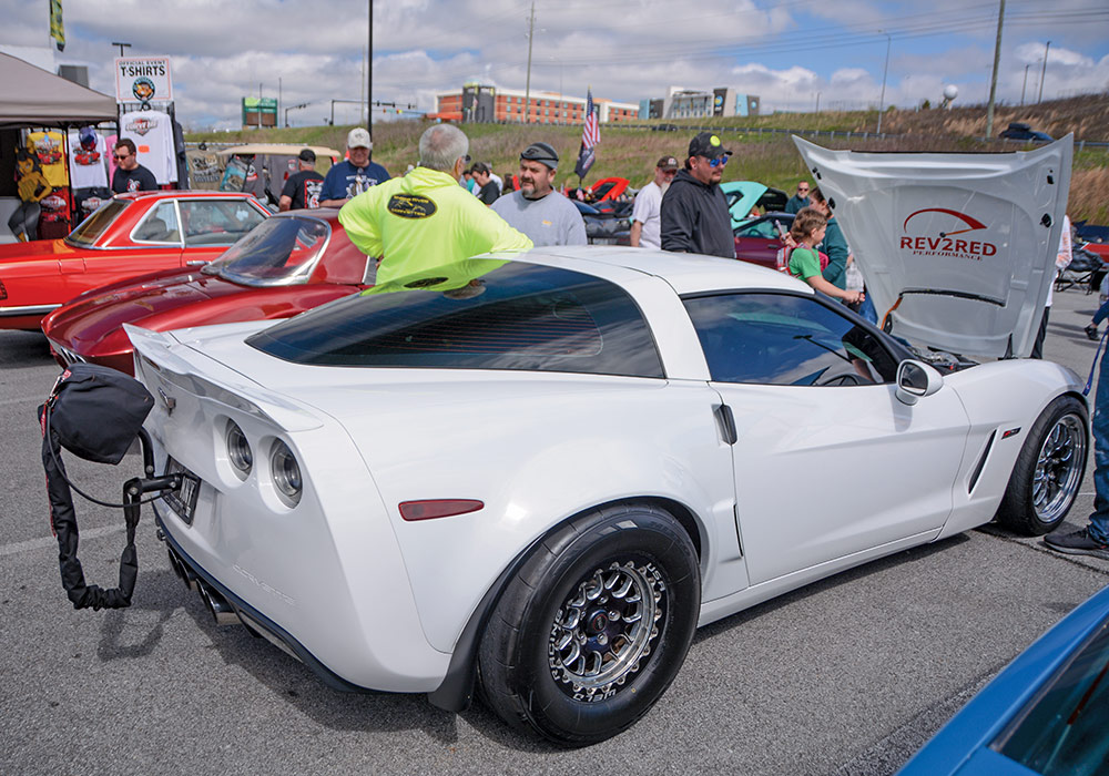 white car with hood open; inside of hood includes a red decal that reads 'rev2red' with a speedometer illustration 