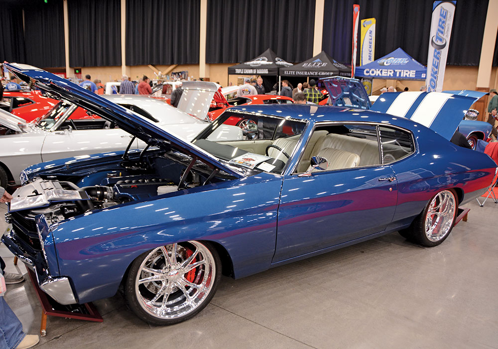 blue car with white white stripe detail on trunk parked indoors with hood and trunk popped open 