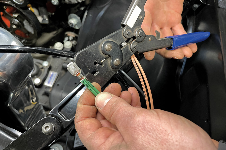 hand using a crimping tool to crimp a wire terminal 