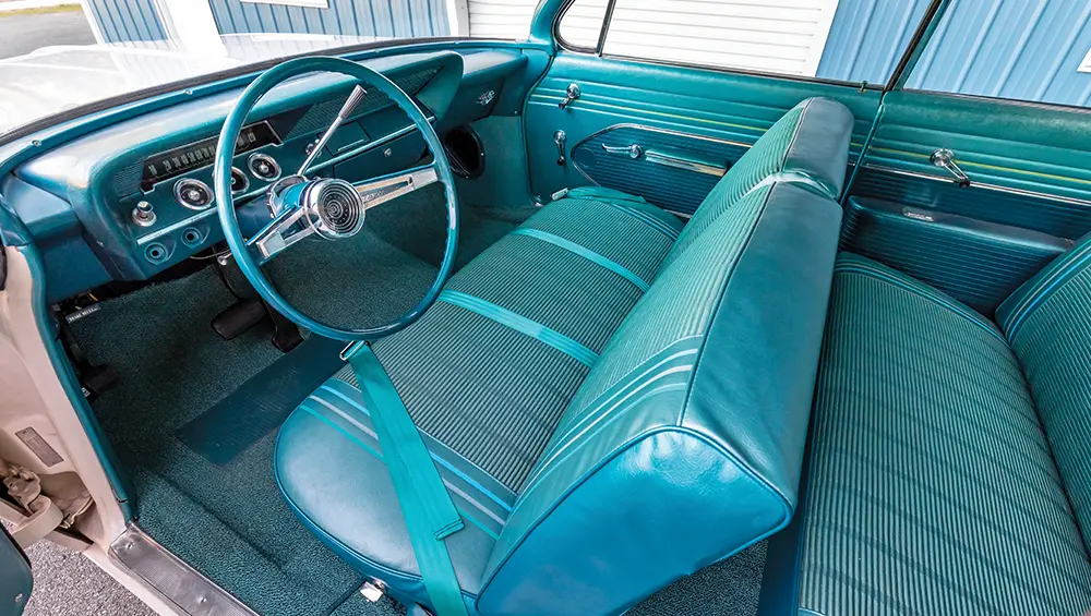 interior view of the ’61 Chevy Bel Air/Biscayne through the driver side door featuring factory original turquoise lined seating along with Classic Industries turquoise carpeting