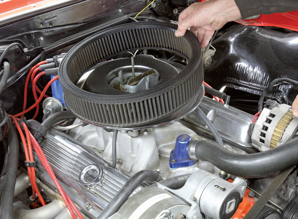 hand holding an air filter above an engine