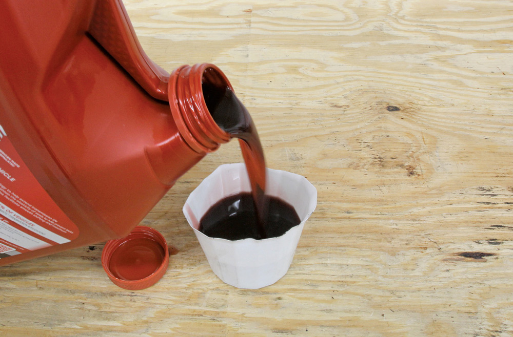 container of oil being poured into a sample cup