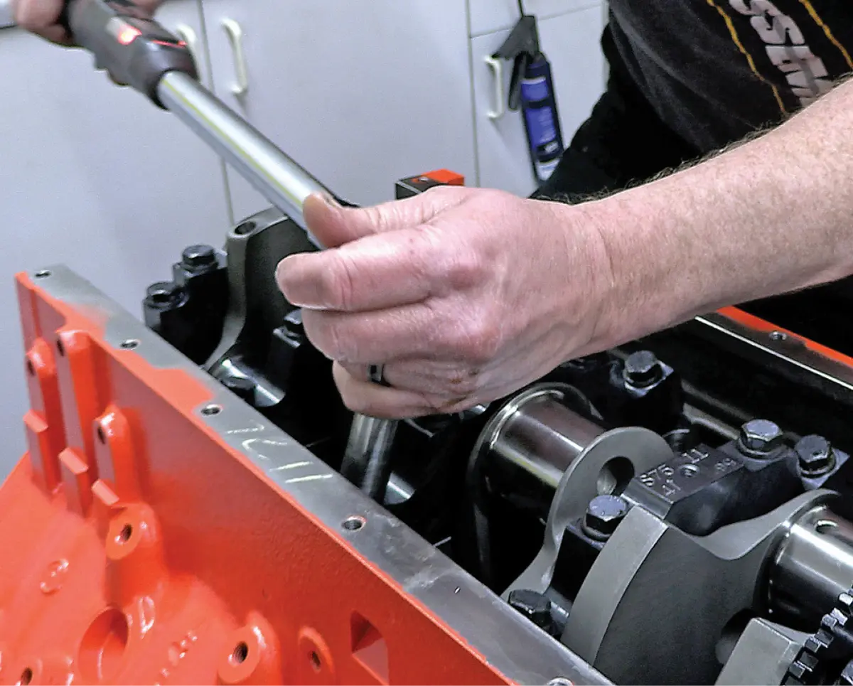 hands use a tool to work on the LS's beefy four-bolt main caps