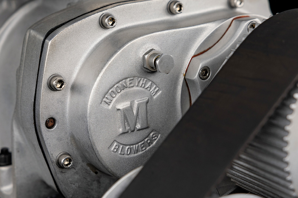 close up of a Mooneyham Blowers logo next to a belt in an engine