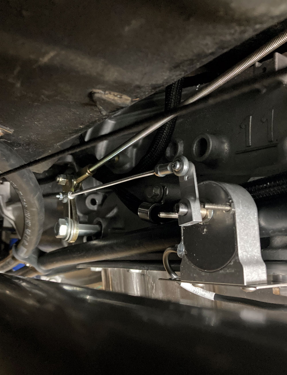 Close-up of the custom shift linkage setup under the 1957 Chevy, showing detailed mechanical work
