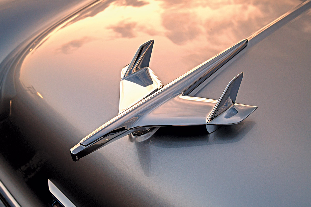 Hood ornament on the 1955 Chevy Bel Air, showcasing the iconic jet-inspired design against the sunset