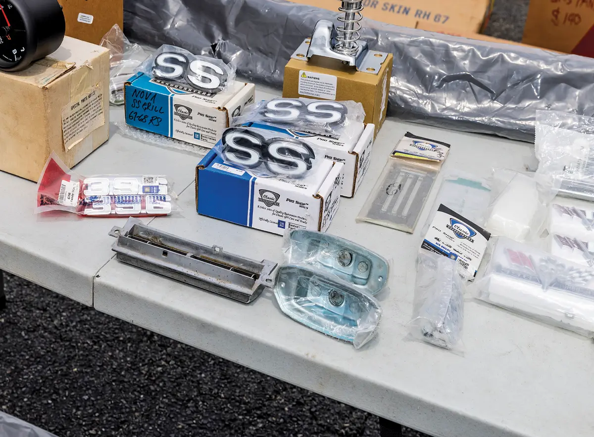 A vendor table showcasing Camaro and Nova SS badges, along with other restoration parts