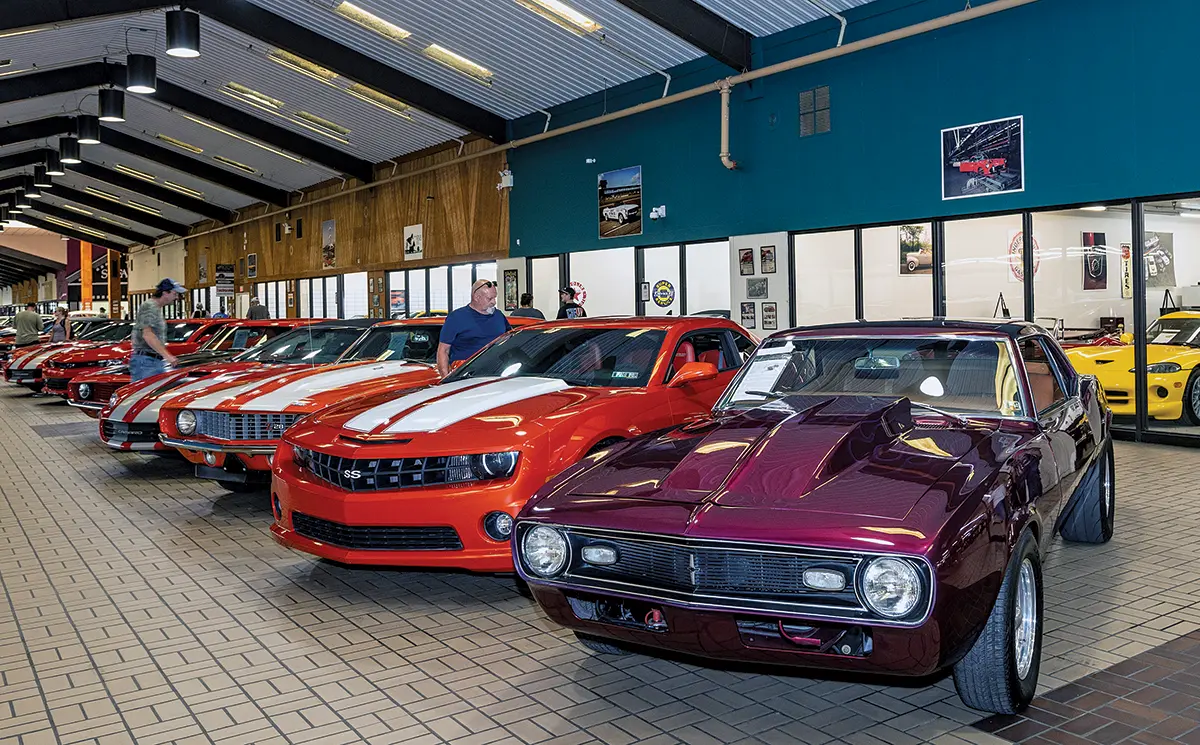 A line of classic and modern Camaros inside a showroom, including a purple custom build in the foreground