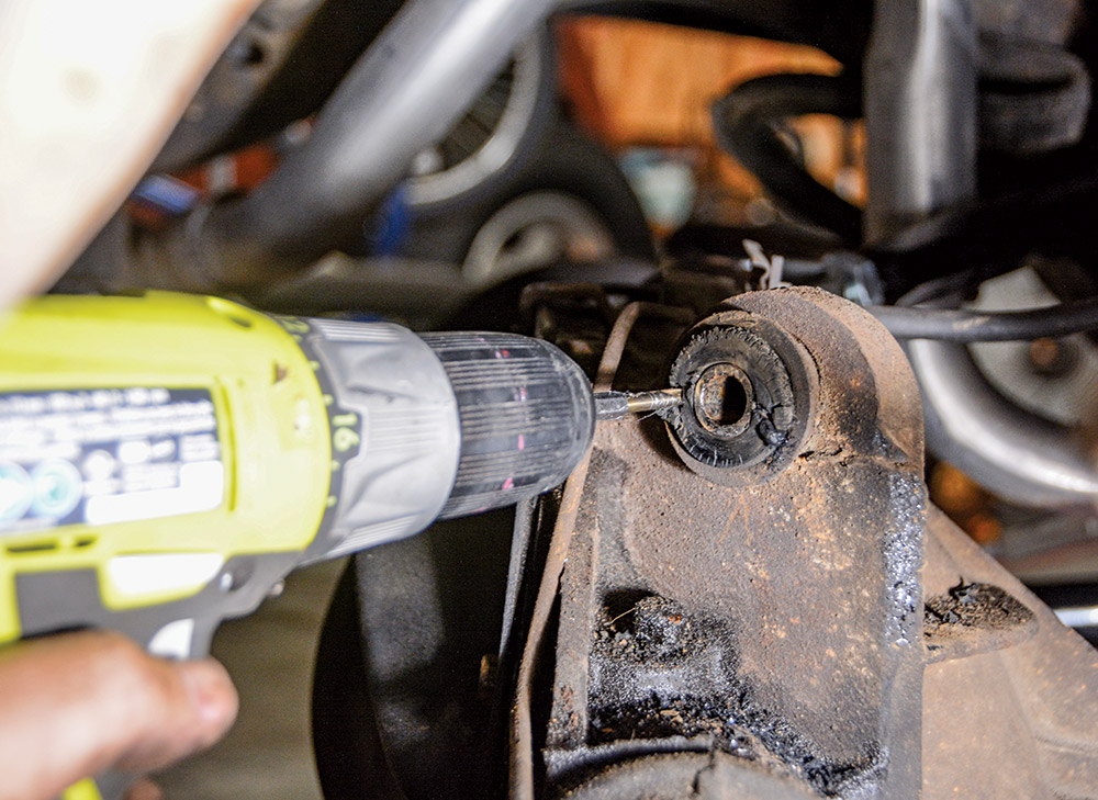 hand using drill to loosen up dirt and debris on bushing
