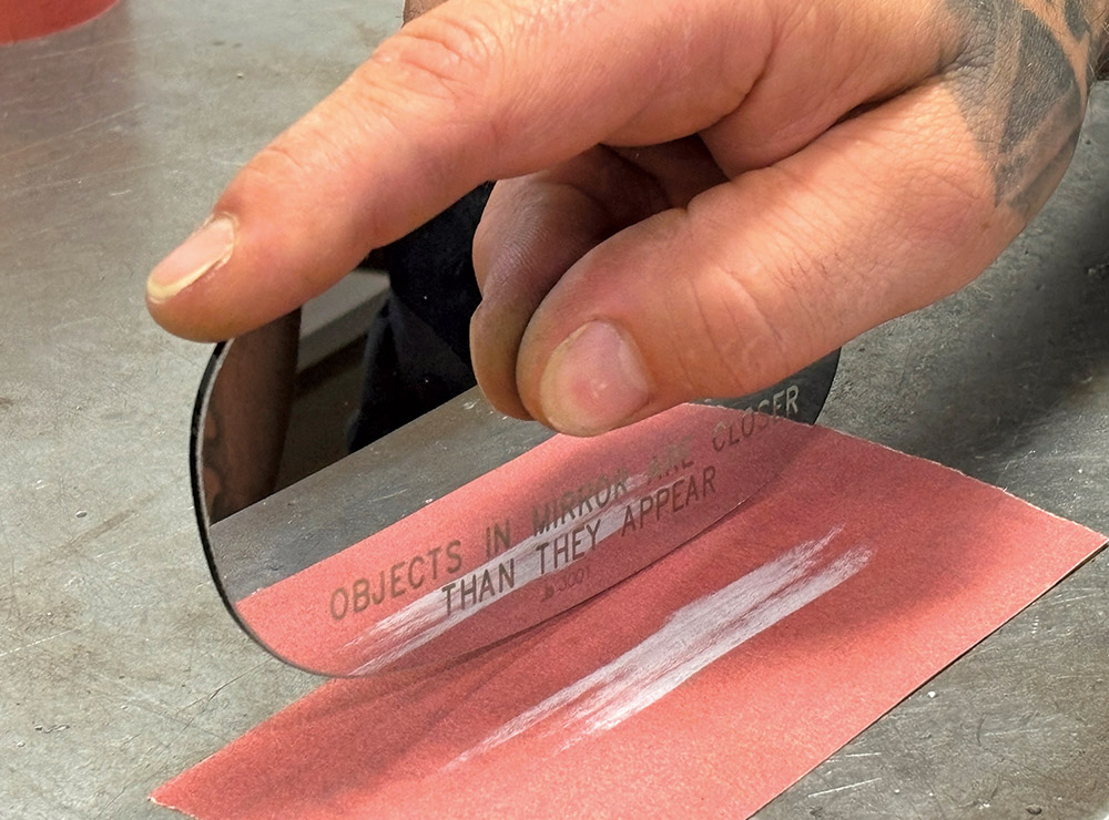 hand holding mirror against sandpaper
