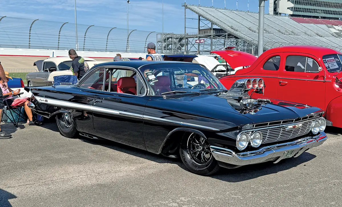 1961 Chevrolet Impala black with a supercharged engine and aggressive stance at the car show