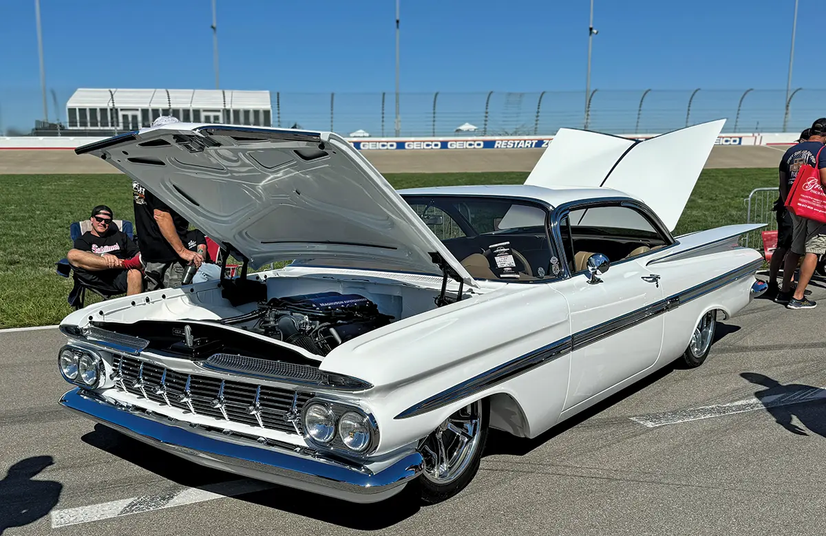 1959 Chevrolet Impala in white with custom wheels and open hood revealing modified engine