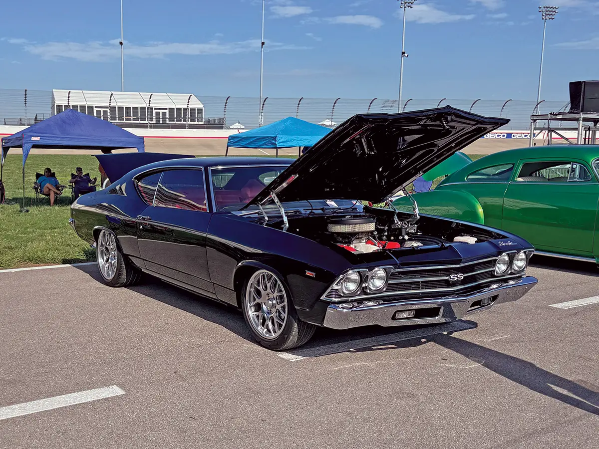 1969 Chevrolet Chevelle SS in black, featuring modern wheels and open hood at the car show