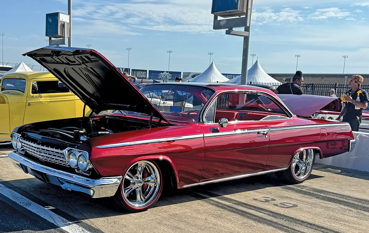1962 Chevrolet Impala in vibrant red with chrome wheels and custom upgrades at the car show
