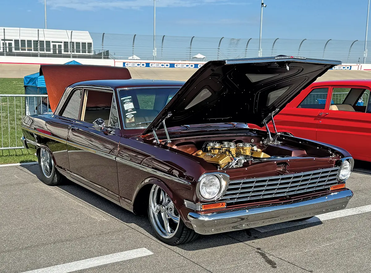 1966 Chevrolet Nova in deep maroon with chrome accents and open hood showing gold engine components