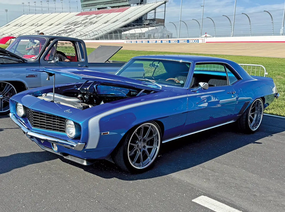 1969 Chevrolet Camaro in bright blue with custom wheels and hood open to reveal engine modifications