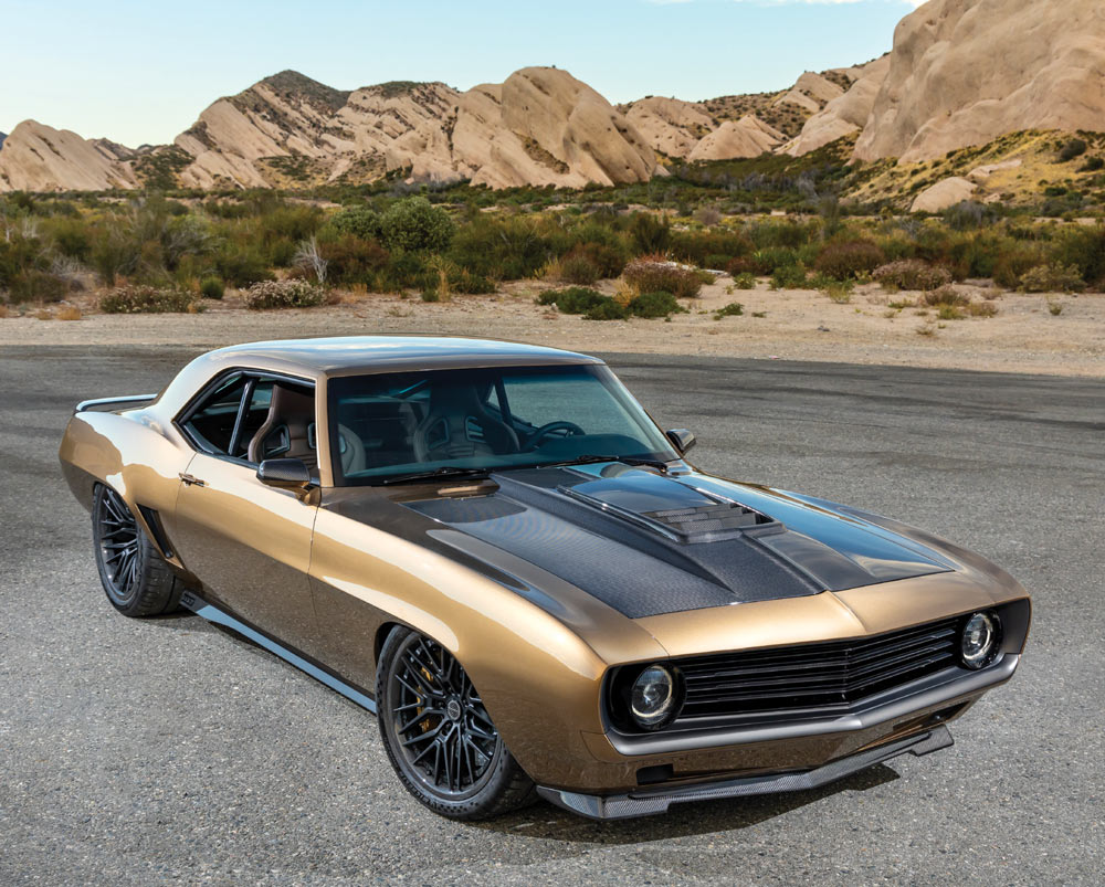 A vintage-style gold and black 1969 Chevy Camaro parked on a desert road.