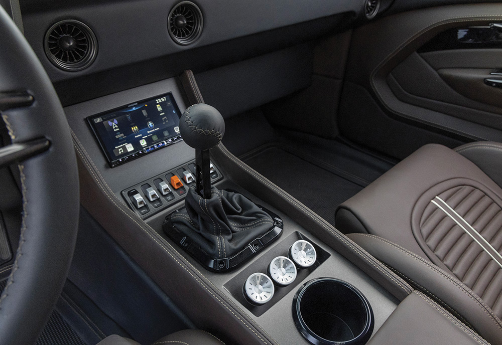 Center console of 1969 Camaro with modern touchscreen display and manual gear shifter