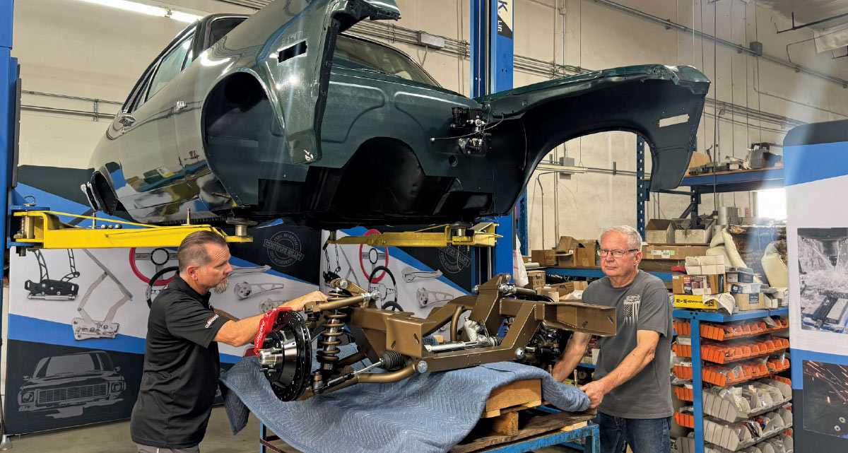 Rear disc brake and suspension setup with a custom-painted axle and control arms on a Chevrolet Nova