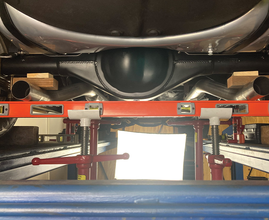 Using a large level and jack stands to ensure even alignment of the exhaust system across the rear axle