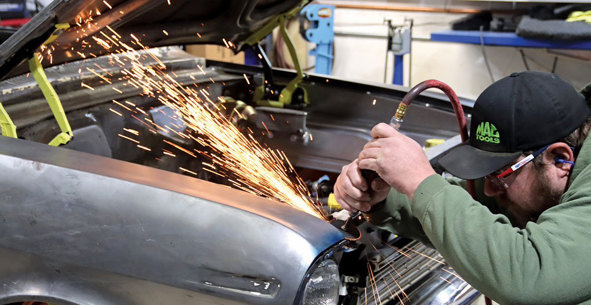a cut-off wheel being used to make short cuts in the edges of the fenders inside the hood opening