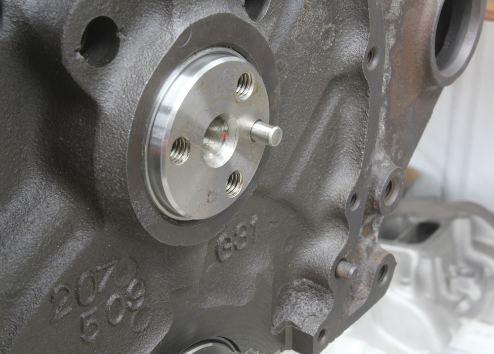 Close-up of a Chevy small-block engine's front face, highlighting the camshaft retainer and freshly machined surface