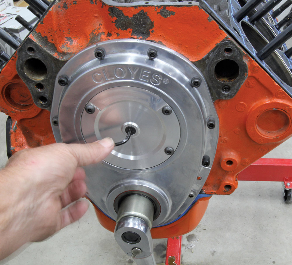 A Chevy small-block engine fitted with a Cloyes timing cover, showing precise alignment and timing setup tools in use