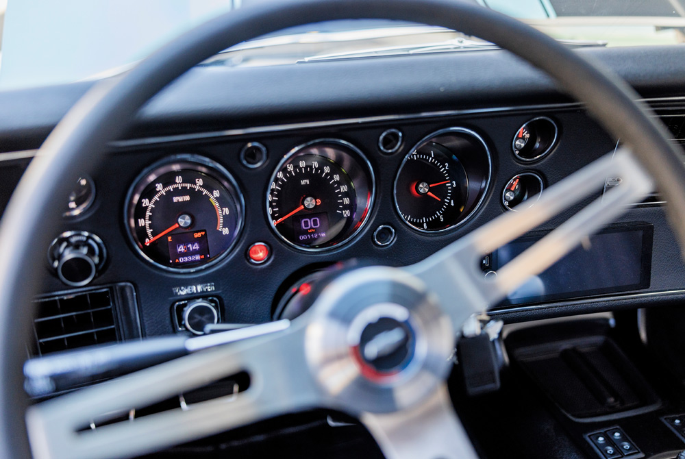 Classic car dashboard with circular gauges and a metallic steering wheel.
