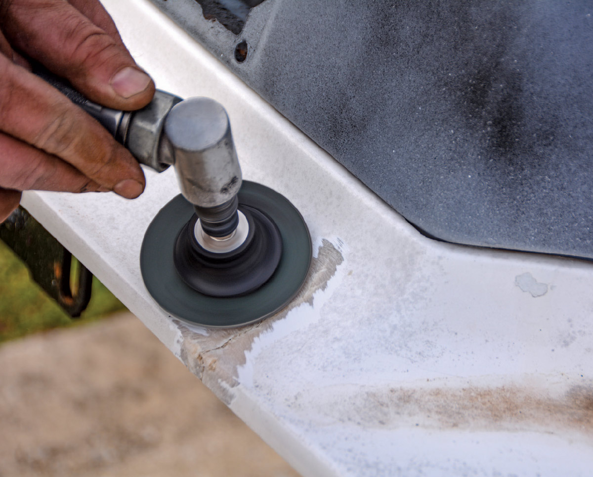 Using a rotary tool to smooth and clean damaged fiberglass panel