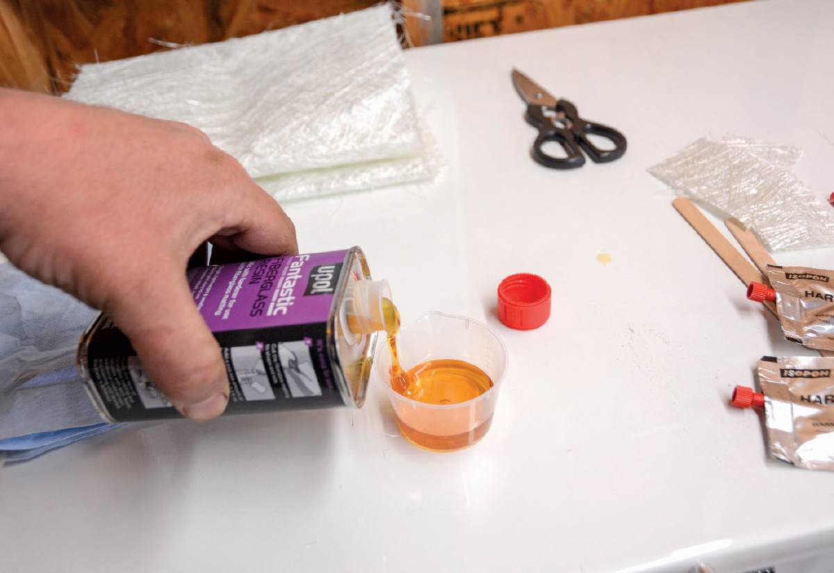 Pouring fiberglass resin into a mixing cup for repair process