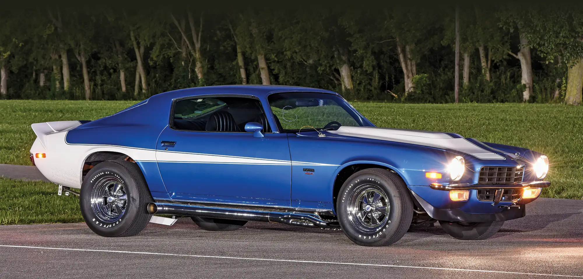 1972 Chevy Camaro Z28 parked with headlights on, showcasing its classic muscle car stance