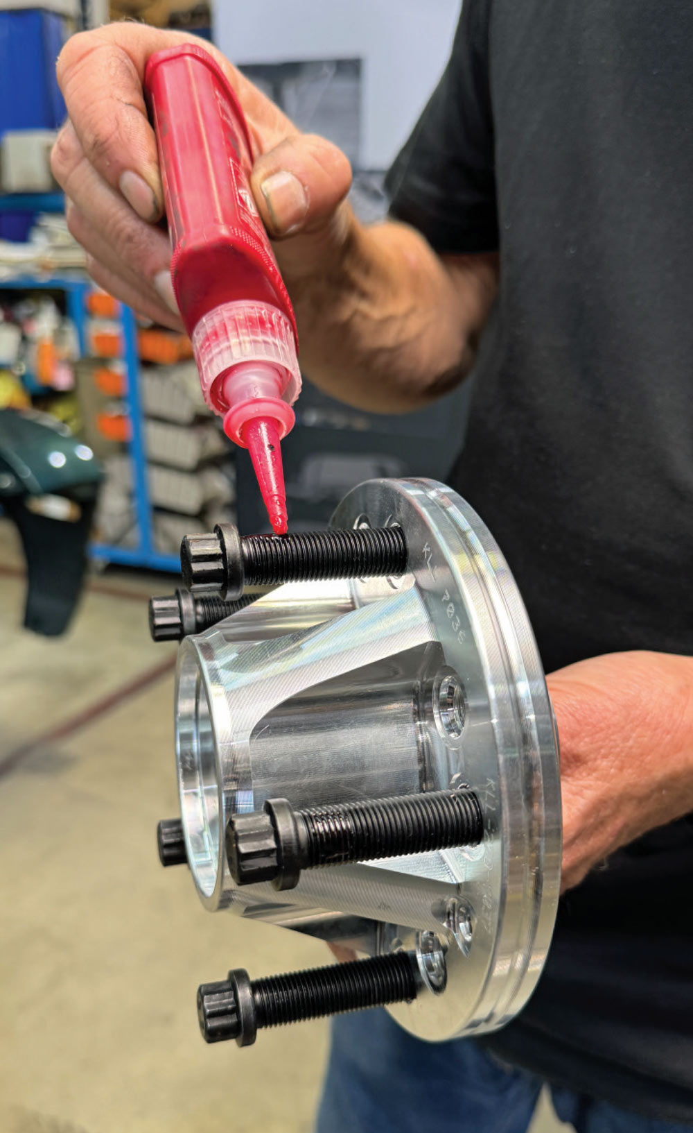 applying thread locker to wheel studs on the 1972 Chevrolet Nova’s brake hub for secure assembly