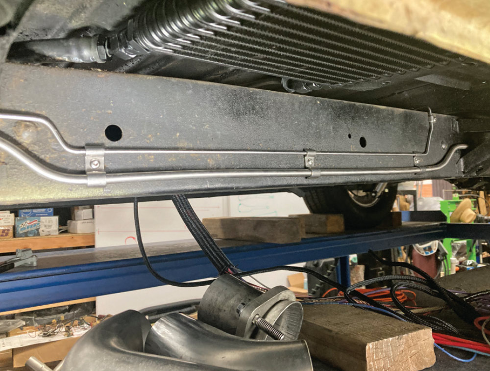 dual fuel lines routed alongside a custom transmission cooler under the frame rail