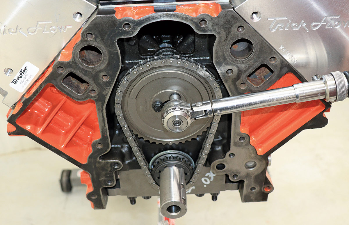 LS3 engine assembly torqueing camshaft sprocket with Trick Flow cylinder heads visible in the background