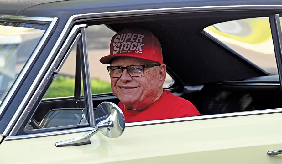 1967 Chevrolet Nova SS with smiling driver in Super Stock hat, adding a personal touch to the classic car