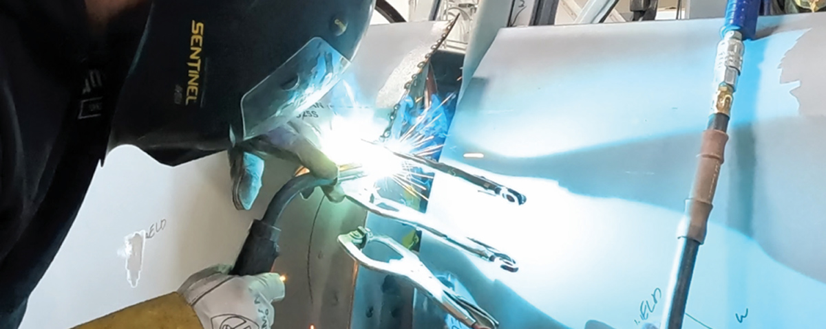 technician carefully finishing weld seams for smooth alignment of door gaps